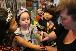 Princess Aliyah Adams is given a sparkly butterfly tattoo done by Marian Ford while Mara Adams and Rei Beams look on.-Photo by McKibben Jackinsky, Homer News