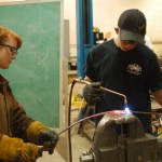 Mady Gerard, left, and Jared Cole, right, students in Mickey Todd’s Homer High School welding class, create the frame for a sculpture being made by Homer Middle School students.