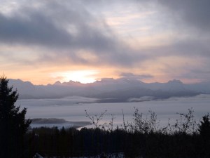The sun rises over the Kenai Mountains while fog covers Kachemak Bay last Thursday morning, a view many Homer workers see on their drive.