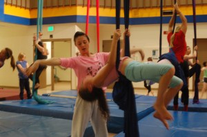 Lauren Winstead, left, an aerialist with Quixotic, teaches Delilah Harris, right, aerial silk techniques on Tuesday in the Homer High School Commons. Quixotic is a Kansas City, Mo., music, dance, circus art and multimedia performance troupe. They perform today and Friday. Both shows are sold out.-Photo by Michael Armstrong, Homer News