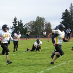 Voznesenka Cougar quarterback Avraam Kalugin, 10, stays a step ahead of Seward Seahawk Preston Attwood, 23, while Kalugin’s teammates David Kuzmin, 55, Markian Polushkin, 62, and Dennis Martishev, 18, clear the way.-Photo by McKibben Jackinsky, Homer News