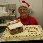 Penny Clements shows off her pretzel-and-frosting model of Ninilchik Trading atop a cake she made for the store’s