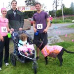 Jeff Williams (center) and Sophia Williams (in stroller) greet runners Brie Drummond, Matt Byrd and Byrd's canine running partner Keala at the end of Sunday's Breast Cancer Run.-Photo by McKibben Jackinsky,  Homer News