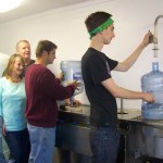 Ohlson Mountain Mineral Springs H2O owners Mary Lou and William Strutz look on while employees Alex Stuart and Jake Worsfold clean and fill bottles. -Photo by McKibben Jackinsky, Homer News