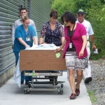 During an evacuation drill at South Peninsula Hospital on Tuesday, a non-ambulatory patient, role-played by Lindsey Yates, is evacuated by hospital staff Martha Roderick, Kelly Luck and Jessie Cashman. In back, Sheridan Bishop of SPH, left, and Bob Becker of Incident Management Solutions, observe.-Photos by McKibben Jackinsky, Homer News
