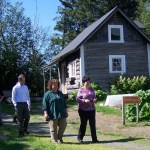 Tabak, Pratt Museum exhibitions curator Scott Bartlett, Pratt Director Diane Converse and Hughes tour the Pratt’s Harrington homestead cabin. -Photo by McKibben Jackinsky, Homer News