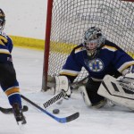 Homer goalie Keegan Strong passes the puck from a failed Kenai goal attempt for Dylan McBride to sweep away from the net.-Photo by Anna Frost, Homer News