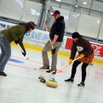 From left to right, Catriona Lowe, Joel Vos and Karen Noyes sweep in front of the stone during  a curling demonstration on Sunday for the Homer Hockey Association’s Kevin Bell Appreciation Day. -Michael Armstrong-Homer News