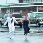 Garrett Butcher and Samantha Jacobsen run through the rain last Saturday at Land’s End Resort for the Homer High School prom. White suits for young men were particularly fashionable at prom this year.-Photo by Anna Frost, Homer News