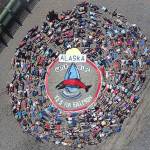 Festival goers and volunteers lie on the ground to form the annual art project at Salmonest on Saturday, Aug. 4, 2018 at the Kenai Peninsula Fairgrounds in Ninilchik, Alaska. The theme of this years presentation, coordinated by Homer artist Mavis Muller, is Water is Life and Yes for Salmon, the latter a reference to a ballot proposition to change Alaska law when it comes to streams and other waters. (Photo courtesy Cook Inletkeeper)