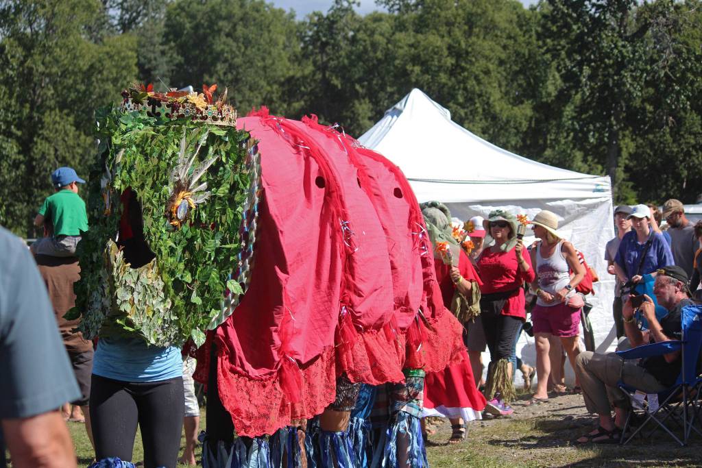 Participants in an aeirial art installation march through the Kenai Peninsula Fairgrounds, with a king salmon leading the way, at this years Salmonfest on Saturday, Aug. 4, 2018 in Ninilchik, Alaska. Homer artist Mavis Muller designs the art installation each year, with a message about salmon or water. (Photo by Megan Pacer/Homer News)