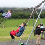 Daniel Kulikov, left, and Addie Moore, center, swing while Aiden Clark, right, stands near the swings during recess Tuesday, Aug. 18, 2018 on the first day of school at West Homer Elementary in Homer, Alaska. (Photo by Megan Pacer/Homer News)