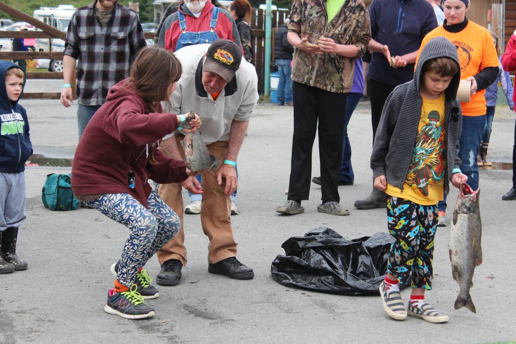 Kenai Peninsula Fair Board President Jim Sterns gives two young children some advice before they participate in the fish toss, an event held every year as part of the fair, on Saturday, Aug. 18, 2018 at the Kenai Peninsula Fairgrounds in Ninilchik, Alaska. (Photo by Megan Pacer/Homer News)