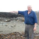 Lee Pedersen, co-owner of the Glacier Drive-In on the Homer Spit, points to the height of beach on Aug. 16, 2018 that eroded last week during a series of storms and high tides in Homer, Alaska. (Photo by Michael Armstrong/Homer News)