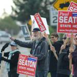 Rep. Paul Seaton, NP-Homer, center, is joined by supporters waving signs on primary election day, Aug. 21, 2018, at the corner of Lake Street and Pioneer Avenue in Homer. Seaton ran unapposed as a nonpartisan candidate for the Alaska Democratic Party seat. Also waving signs are supporters of Alyse Galvin, a nonpartisan candidate for the Democratic Party seat for U.S. Congress. (Photo by Michael Armstrong/Homer News)