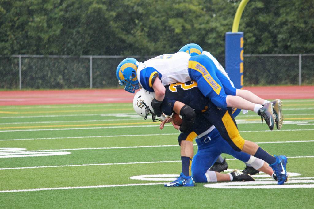 Homer junior Noah Fisk hoists a Monroe Cathloic High School player trying to tackle him as he runs the ball during their Saturday, Aug. 25, 2018 game at the high schools turf field in Homer, Alaska. Monroe eked out a slim win over the Mariners 28-27. (Photo by Megan Pacer/Homer News)