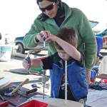 Jen Fonkert helps her four-year-old son, Beau, drill a hole into a wooden boat he made Saturday, Sept. 1, 2018 at the Kachemak Bay Wooden Boat Festival on the Homer Spit in Homer, Alaska. (Photo by Megan Pacer/Homer News)