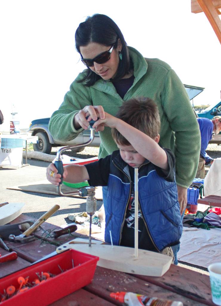 Jen Fonkert helps her four-year-old son, Beau, drill a hole into a wooden boat he made Saturday, Sept. 1, 2018 at the Kachemak Bay Wooden Boat Festival on the Homer Spit in Homer, Alaska. (Photo by Megan Pacer/Homer News)