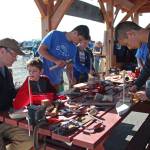 A group of boys and men construct various wooden boats Saturday, Sept. 1, 2018 during the Kachemak Bay Wooden Boat Festival on the Homer Spit in Homer, Alaska. (Photo by Megan Pacer/Homer News)