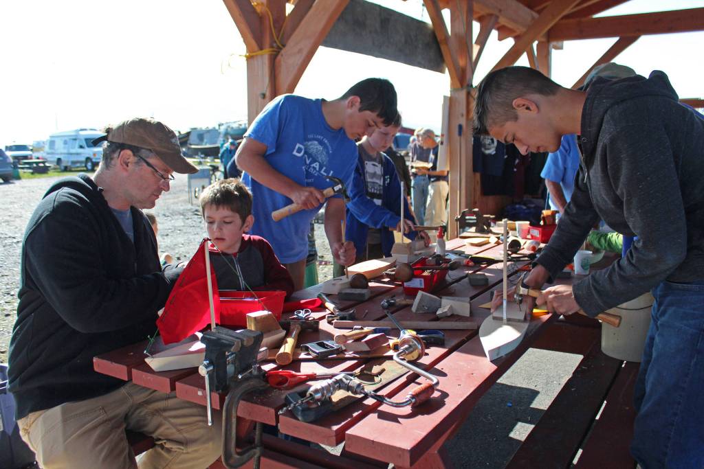 A group of boys and men construct various wooden boats Saturday, Sept. 1, 2018 during the Kachemak Bay Wooden Boat Festival on the Homer Spit in Homer, Alaska. (Photo by Megan Pacer/Homer News)