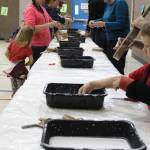 Parents and their children work on making violins out of cardboard and glue during a craft session Thursday, Sept. 6, 2018 at Paul Banks Elementary School in Homer, Alaska. The project is part of the schools Preludes Violin Program, which teaches first and second grade students musicianship and the host of skills that come with it. Students start out with the cardboard violins before graduating to the real instruments later in the year. (Photo by Megan Pacer/Homer News)