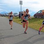 Homers Sienna Carey rushes to pass two Soldotna High School cross-country runners at the finish line of the girls 5K race Friday, Sept. 7, 2018 during the Homer Invitational held on the Homer Spit in Homer, Alaska. (Photo by Megan Pacer/Homer News)
