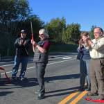 Members of the Homer City Council and Save-U-More Assistant Manager Brian Nahmis (second from left) celebrate after council member Shelly Erickson (third from left) cuts a ribbon in a grand opening ceremony for the completed Greatland Street on Tuesday, Sept. 25, 2018 in Homer, Alaska. (Photo by Megan Pacer/Homer News)