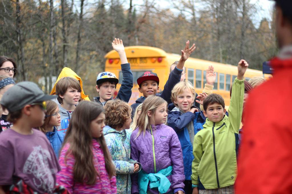 Students raise their hands to answer a question during an educational trip Thursday, Oct. 4, 2018 to the Anchor River in Anchor Point, Alaska. The egg take event is the first part of a year-long Salmon in the Classroom program. (Photo by Megan Pacer/Homer News)