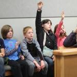 Grace Berumen and Madelyn Madrid raise their hands to ask questions during an Oct. 8, 2018 field trip to the Homer Courthouse in Homer, Alaska. They and their fellow Fireweed Academy classmates learned about the law and the inn workings of the courthouse. (Photo by Megan Pacer/Homer News)