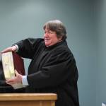 Homer District Court Judge Margaret Murphy holds up one of several volumes of laws to show a groups of Fireweed Academy students during their Oct. 8, 2018 field trip to the Homer Courthouse in Homer, Alaska. She showed them the book in response to a students question of: How many law are there? (Photo by Megan Pacer/Homer News)