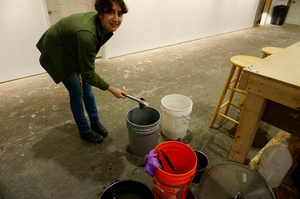 Elissa Pettibone checks on nylon string being dyed in natural pigments at The Shop on Tuesday, Oct. 16, 2018, in Kachemak City, Alaska. (Photo by Michael Armstrong/Homer News)