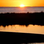 The sun sets over the Aleutian Range and is reflected in Mariner Park Lagoon on Monday, Oct. 29, 2018, in Homer, Alaska. (Photo by Michael Armstrong/Homer News)