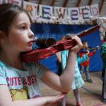 First grade student Elizabeth Parke practices holding a cardboard violin, in anticipation of the real thing, at Fireweed Academy in Homer, Alaska. (Photo by Miranda Weiss)