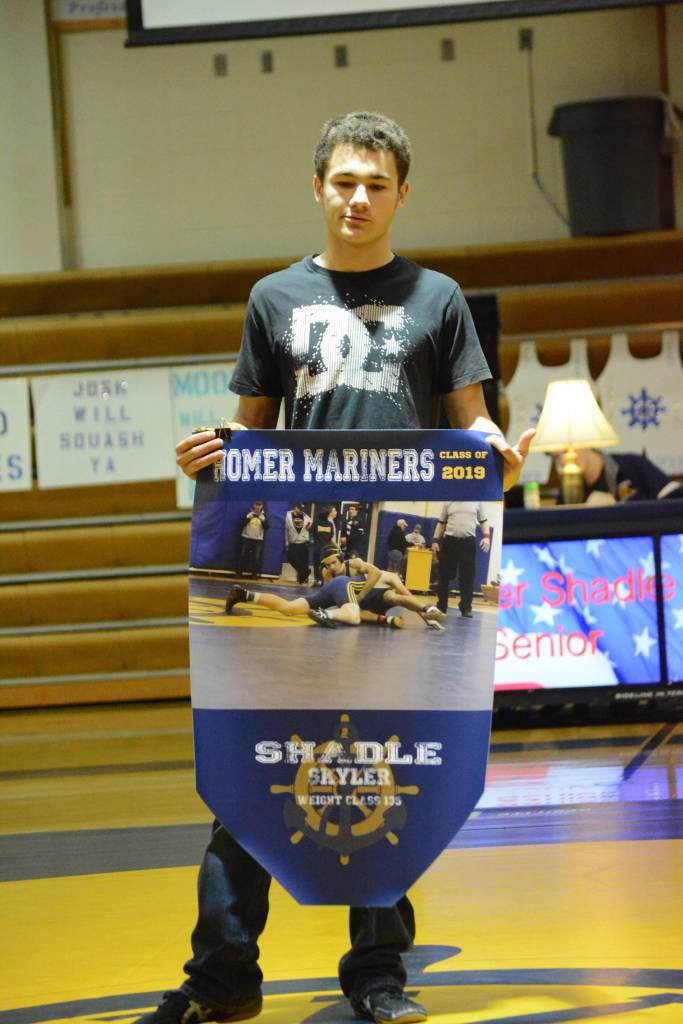 Homer High School senior Skyler Shadle, son of Jackie Eisenberg, holds a banner recognizing him at Senior Night, the Homer-Kenai dual wrestling meet held Nov. 21, 2018, in the Homer High School Alice Witte Gym, Homer, Alaska. (Photo by Michael Armstrong/Homer News)