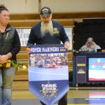 Tammie Cook, left, and Todd Cook, right, holds a banner recognizing their daughter, McKenzie Cook, at Senior Night, the Homer-Kenai dual wrestling meet held Nov. 21, 2018, in the Homer High School Alice Witte Gym, Homer, Alaska. (Photo by Michael Armstrong/Homer News)