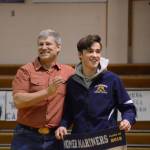 Seth Inama holds a banner recognizing him at Senior Night, the Homer-Kenai dual wrestling meet held Nov. 21, 2018, in the Homer High School Alice Witte Gym, Homer, Alaska. Supporting him is his father, Jay Inama. (Photo by Michael Armstrong/Homer News)