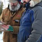 Musher Cim Smyth, right, checks in to the first rest stop in this years Tustumena 200 Sled Dog Race on Saturday, Jan. 26, 2019 at McNeil Canyon Elementary School east of Homer, Alaska. (Photo by Megan Pacer/Homer News)