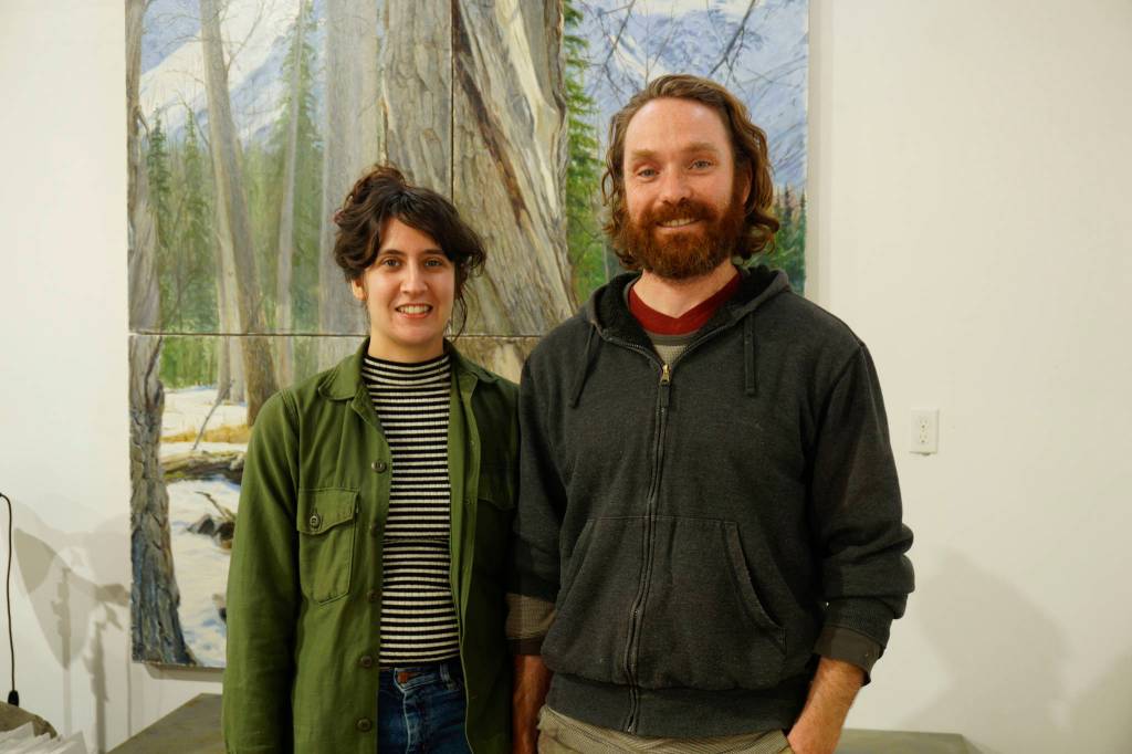 Elissa and David Pettibone pose on Tuesday, Oct. 16, 2018, by one of David Pettibones paintings at The Shop, an art space the Pettibones started in August 2018 in Kachemak City, Alaska. (Photo by Michael Armstrong/Homer News)