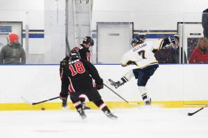 Homer skater Tyler Gilliland, having lost his stick, kicks the puck out of a scuffle with two Kenai Central High School players during a Tuesday, Jan. 8, 2019 game at the Kevin Bell Ice Arena in Homer, Alaska. (Photo by Megan Pacer/Homer News)