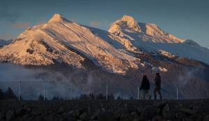 In this Jan. 8, 2018 photo, a couple walks along the Airport Dike Trail as the evening light shines on Mt. McGinnis, left, and Stroller White Mountain. (Michael Penn | Juneau Empire File)