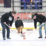 Mike Kozloski (left), Chuck Bowman (center) and Steve Nelzen work together to deliver and sweep a curling stone during a Learn to Curl fundraiser event for the Homer Curling Club on Saturday, Jan. 12, 2019 at the Kevin Bell Arena in Homer, Alaska. The clinic was taught by former Olympic curler Jessica Schultz. (Photo by Megan Pacer/Homer News)