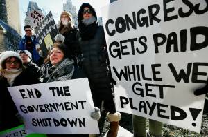 Government workers and their supporters hold signs during a protest in Boston, Friday, Jan.11, 2019. The workers rallied with Democratic U.S. Sen. Ed Markey and other supporters to urge that the Republican president put an end to the shutdown so they can get back to work. (AP Photo/Michael Dwyer)