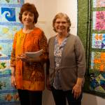 Patrice Krant, left, and Janet Bacher, right, stand by their quilts in the 9 Women / 9 Quilts show that opened last Friday, Feb. 1, 2019, at the Homer Council on the Arts, in Homer, Alaska. (Photo by Michael Armstrong/Homer News)