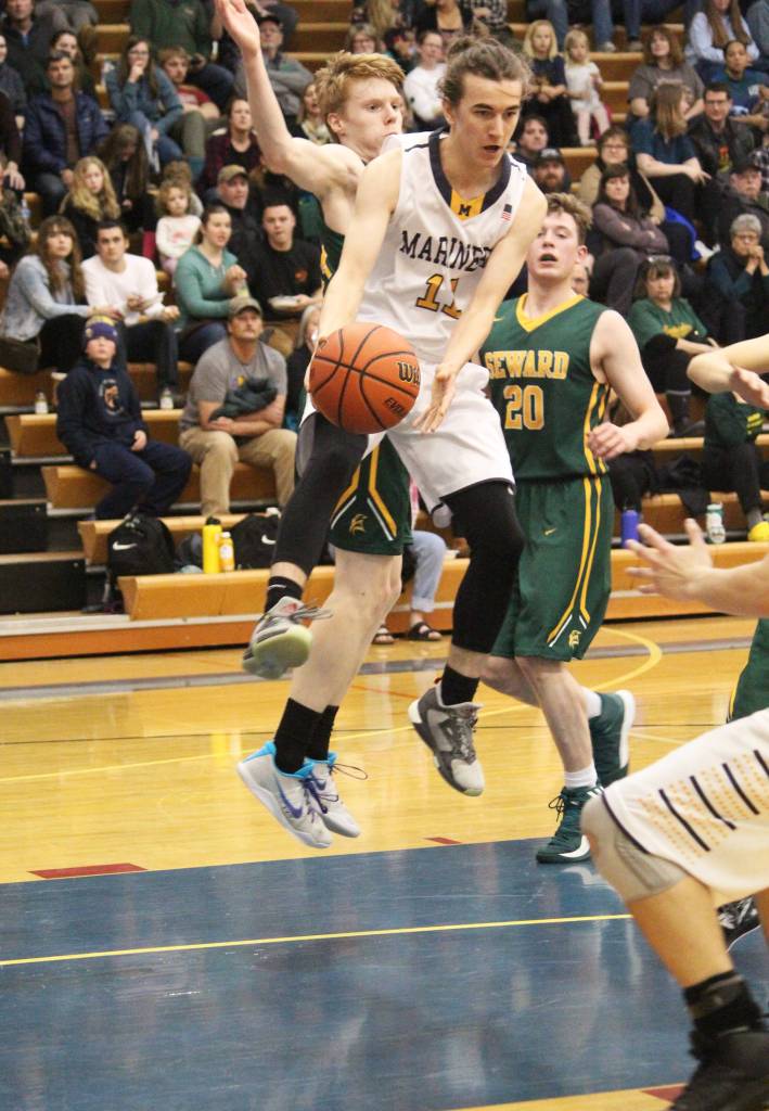Homers Daniel Reutov sends the ball to a teammate under pressure from Seward players Friday, Feb. 8, 2019 during the Winter Carnival Basketball Tournament in Homer, Alaska. (Photo by Megan Pacer/Homer News)