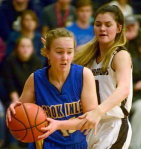 Cook Inlet Academys Addie Nelson drives on Nikolaevsks Justina Fefelov on Friday, March 1, 2019, in the Peninsula Conference finals at Cook Inlet Academy. (Photo by Jeff Helminiak/Peninsula Clarion)