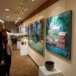 Franco and Caroline Venuti look at John Fenskes paintings at the First Friday, April 5, 2019, opening for his retrospective showing at Kachemak Bay Campus in Homer, Alaska. (Photo by Michael Armstrong/Homer News)