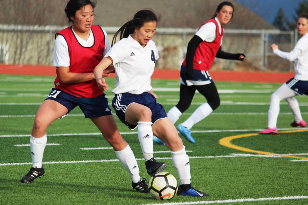 Soldotnas Meijan Leaf fights to keep possession of the ball under pressure from Homers Alyssum Veldstra during a Tuesday, April 9, 2019 game in Homer, Alaska. The teams tied the game 3-3. (Photo by Megan Pacer/Homer News)