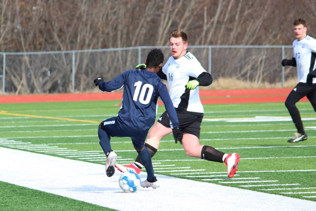 Homers Eyoab Knapp taps the ball behind himself to avoid Nikiskis Seth DeSiena during a Tuesday, April 23, 2019 soccer game at Homer High School in Homer, Alaska. (Photo by Megan Pacer/Homer News)