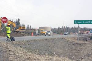 A construction worker directs traffic near the intersection of the Kenai Spur Highway and Beaver Loop Road on Tuesday, April 23, 2019, in Kenai, Alaska. Construction work on multiple roads will continue through the summer. (Photo by Erin Thompson/Peninsula Clarion)