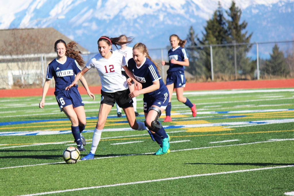 Mariners Eve Brau, left, and Brenna McCarron, right, edge a Grace Christian player out of the action during Fridays varsity soccer game on April 26, 2019, at the high school in Homer, Alaska. (Photo by McKibben Jackinsky).
